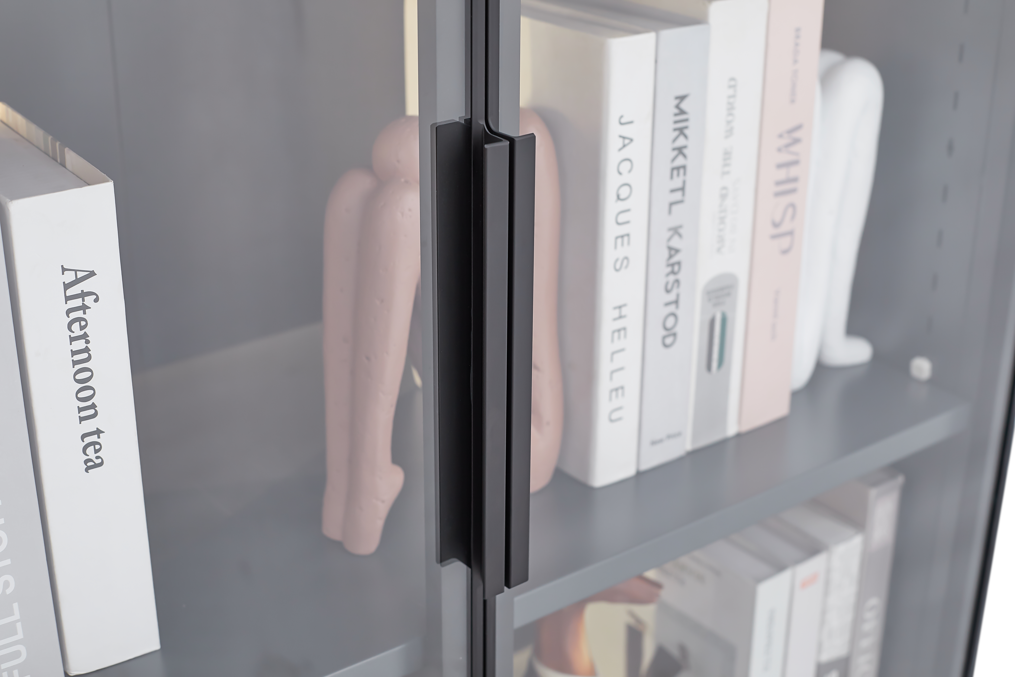 Close-up of a modern grey display storage cabinet with adjustable shelves, featuring books and decorative items.